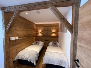 two beds in a room with wooden walls at Alpine Lodge Brixen in Brixen im Thale