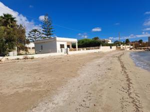 a dirt road leading to a white building on the beach at Villino Relax in Portopalo