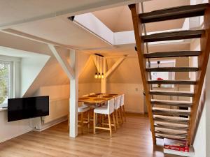 a dining room with a table and chairs and a staircase at Dat Höhnerstübche Apartment in Siegen