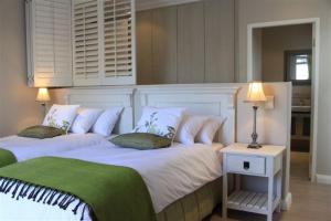 a bedroom with two beds and a table with a lamp at Spatalla Holiday Homes in Kleinmond