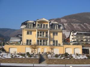 ein großes gelbes Haus vor einem Berg in der Unterkunft Residenz Moselstausee in Sankt Aldegund