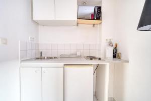 a white kitchen with a sink and a microwave at Abelia-Confort et Sérénité au coeur de la ville in Palaiseau +5 photos