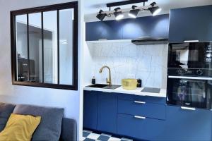 una cucina con mobili blu e un lavandino di L'Instant WOW! a Cahors