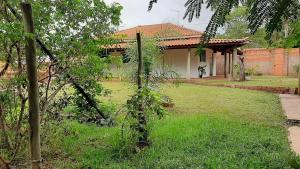 een tuin met een huis en een erf met een boom bij Chácara agradável com piscina in Brotas