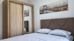 a bedroom with a bed with white sheets and a mirror at NY Apartment, two bedrooms in Tivat