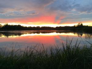 a sunset over a lake with the sun setting at Nad stawami in Wilka +9 photos