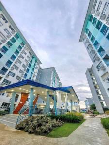 a building with a blue and orange structure next to two tall buildings at Wanderer's Home at Seawind Condo near Davao Airport in Davao City