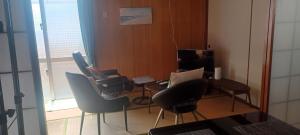 a room with chairs and a table and a television at Miyagi Apartment Tomari in Naha