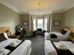 a hotel room with two beds and a desk at Headlands Hotel in Llandudno