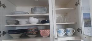 a cabinet filled with plates and cups and bowls at Miyagi Apartment Tomari in Naha +3 photos
