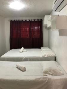 two beds in a room with a red window at Linhares hospedagem in João Pessoa