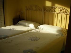 Duas camas num quarto com lençóis brancos e flores em Posada laventa em Selaya