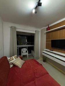 a living room with a red couch and a television at Apartamento quadra mar, 1 dos quartos com ar-condicionado , Barra Sul in Balneário Camboriú +8 photos