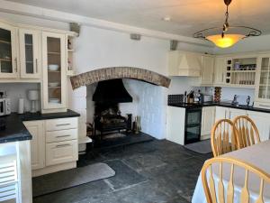 a kitchen with a fireplace in a kitchen with white cabinets at Gragara House in Kilkenny