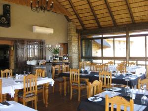 a dining room with tables and chairs and windows at Cheetau Lodge in Ebenhaezer