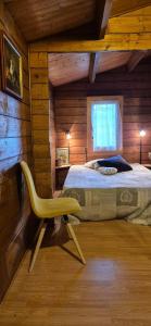 une chambre avec un lit et une chaise jaune dans l'établissement La Corbassière, à Murs-et-Gélignieux