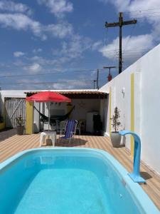 a swimming pool in front of a house with an umbrella at Casa Lagoa & Praia in Estância