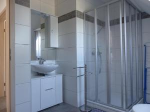 a white bathroom with a sink and a shower at Ferienhaus Roebel Mueritz in Marienfelde +1 photo