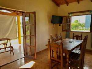 comedor con mesa de madera y TV en Cabañas Amore Mío, en Mina Clavero
