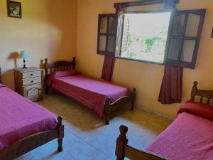 Un dormitorio con dos camas y una ventana. en Cabañas Amore Mío, en Mina Clavero