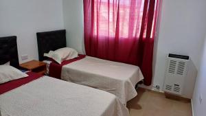 a room with two beds and a window with red curtains at Complejo CRISMAR in Las Grutas