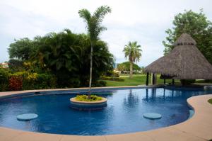 a swimming pool with a palm tree in the middle at El Tigre, Green Bay I Shared Pool in Nuevo Vallarta 