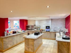 a large kitchen with red walls and a large counter at Four Saints Brig Y Don Hotel in Llandudno