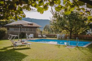 a swimming pool in a yard with chairs and an umbrella at Luisashaus in Tirolo