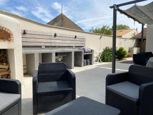 Un patio con sillas y un banco y una parrilla. en Villa L'Oasis, en Aytré