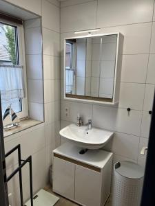 a white bathroom with a sink and a mirror at Ferienhaus Liesel in Dornumersiel +14 photos
