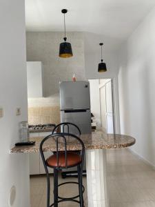 a kitchen with a counter with two chairs and a refrigerator at samia fekih in El Hafsi