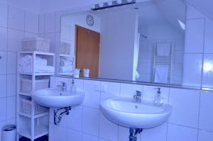 a white bathroom with two sinks and a mirror at zentrumsnahe Ferienwohnung im Grünen in Röbel +7 photos