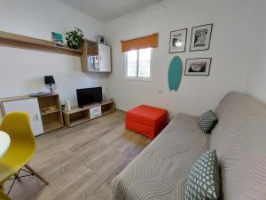 een woonkamer met een bank en een rode kruk bij Buenas Olas Tenerife in Costa Del Silencio