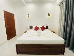 a bedroom with a bed with white sheets and red pillows at Lavish in Weligama +20 photos