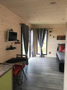 Cette chambre dispose d'un lit, d'une télévision et de quelques fenêtres. dans l'établissement La Roulotte - Tiny House 150m de la Plage, à Portbail