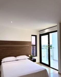 a bedroom with a white bed and a large window at Hotel Duna Real in Uribia