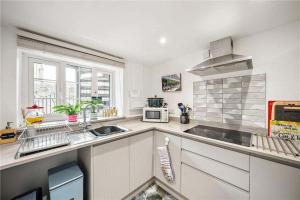a white kitchen with a sink and a microwave at Rivulet Cottage in Pateley Bridge