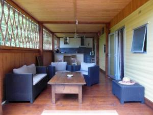 a porch with couches and a table and a kitchen at Chalet Alice in LʼHôpital-Saint-Blaise