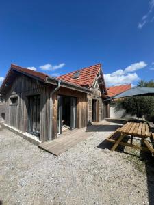 a wooden cabin with a picnic table and an umbrella at Maison de vacances 4 étoiles, Mimizan plage sud in Mimizan-Plage