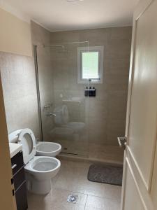 a bathroom with a toilet and a glass shower at Cabaña Puente B 1 in El Calafate