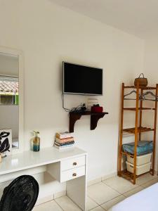 a room with a desk and a television on a wall at Microcasa Aconchego Paraty in Paraty
