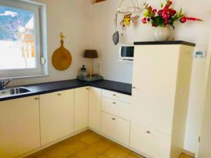 a kitchen with white cabinets and a vase of flowers at Villa Sonnenpiste in Kötschach