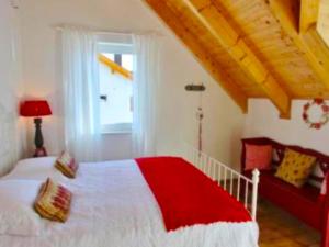 a bedroom with a red and white bed and a window at Villa Sonnenpiste in Kötschach