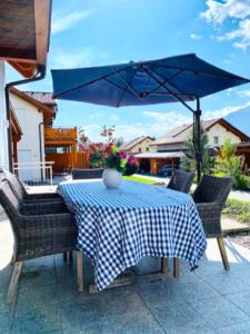 a table and chairs with a blue and white checkered umbrella at Villa Sonnenpiste in Kötschach