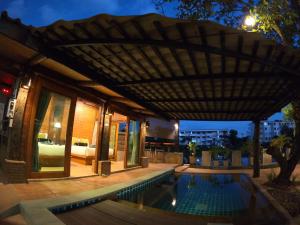 a patio with a swimming pool under a pergola at Tolani Riverside Villa in Chiang Mai