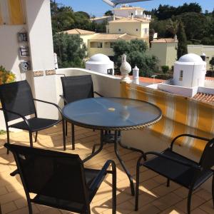 a glass table and chairs on a balcony at Casa Caracol in Praia do Carvoeiro