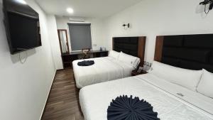a hotel room with two beds and a flat screen tv at Hotel ANB Aeropuerto Guadalajara in Guadalajara +48 photos