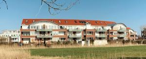 a large building with a red roof on a field at Direkt am Deich! Ferienwohnung de Prigg in Dorum Neufeld