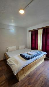 a large bed in a room with red curtains at Old Street House and Cafe in Manāli