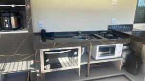 una cocina con fregadero y microondas en Hostel quartos privados Ouvidor, en Garopaba 29 fotos más